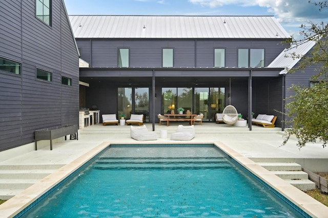 rear view of house featuring metal roof, an outdoor pool, and a patio