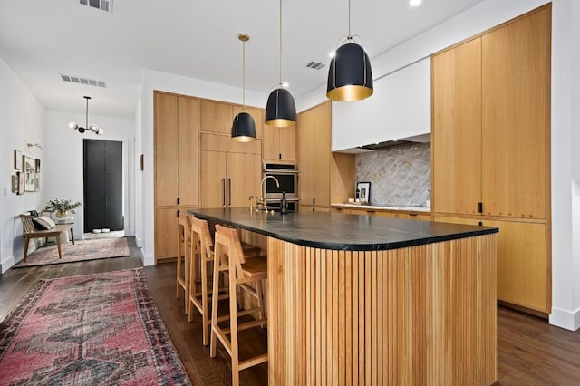 kitchen with dark wood-style floors, dark countertops, visible vents, decorative backsplash, and paneled refrigerator