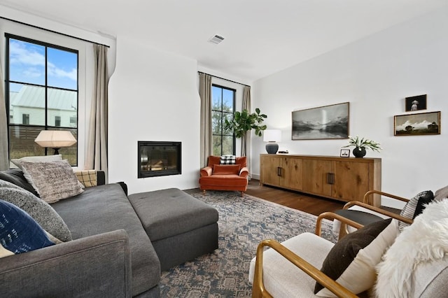 living room featuring a glass covered fireplace, visible vents, and wood finished floors