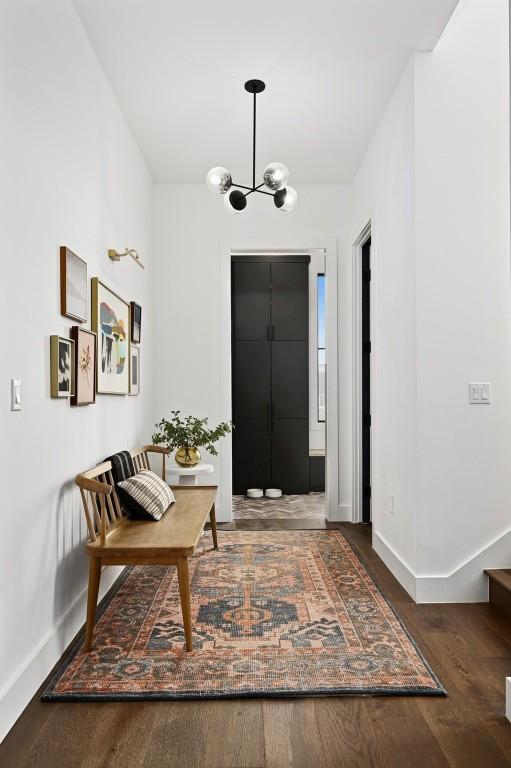 foyer entrance with a chandelier, baseboards, and wood finished floors