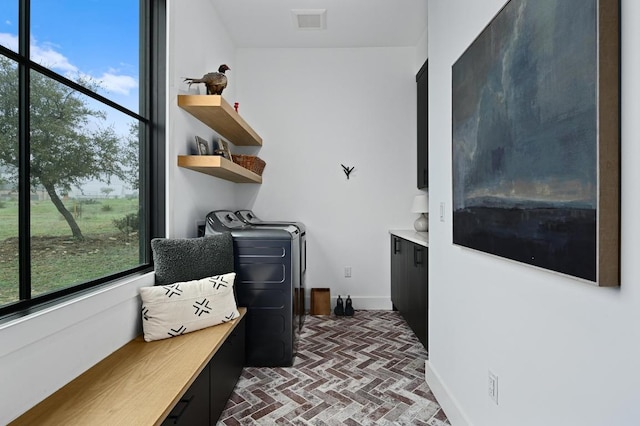 clothes washing area with laundry area, baseboards, visible vents, independent washer and dryer, and brick floor