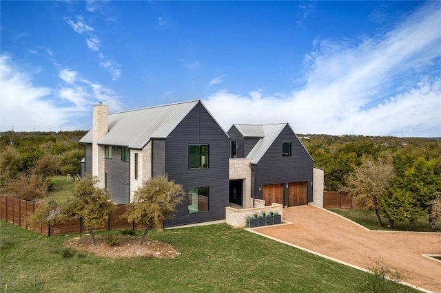 modern farmhouse with metal roof, fence, dirt driveway, a front lawn, and a chimney