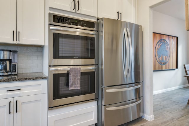 116 Evening Star Ln, Georgetown, TX 78628 - kitchen featuring stainless steel appliances, baseboards, dark stone countertops, decorative backsplash, and white cabinets