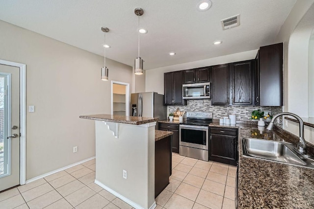 kitchen with light tile patterned floors, stainless steel appliances, a sink, a center island, and tasteful backsplash