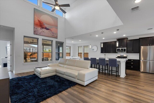 living area with visible vents, a ceiling fan, dark wood-style flooring, and a wealth of natural light