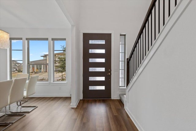 foyer featuring baseboards, stairs, and wood finished floors