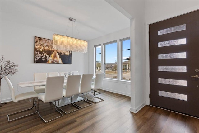 dining area with baseboards, dark wood finished floors, and a notable chandelier