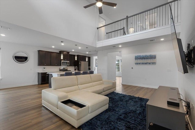 living room with baseboards, ceiling fan, visible vents, and wood finished floors
