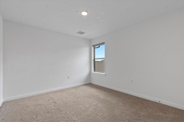 carpeted empty room featuring baseboards and visible vents