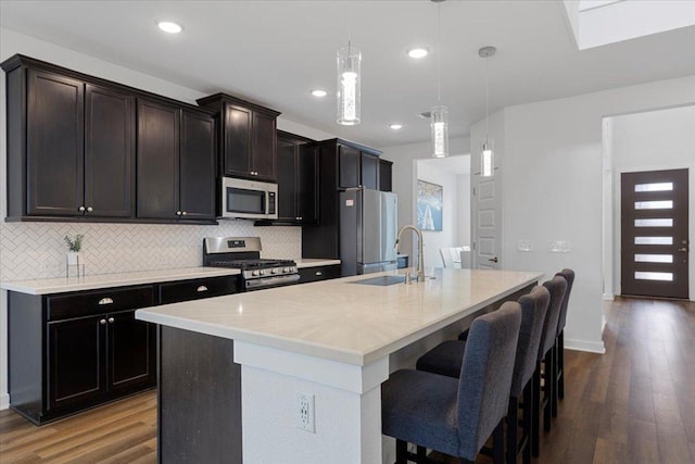 kitchen with a sink, a kitchen island with sink, wood finished floors, and stainless steel appliances