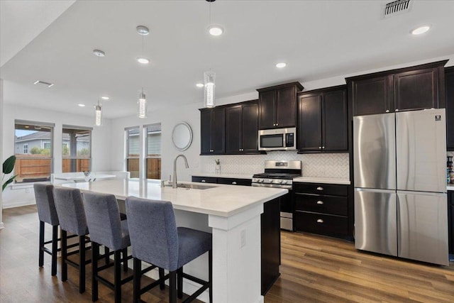 kitchen featuring decorative backsplash, visible vents, a sink, stainless steel appliances, and dark wood-type flooring