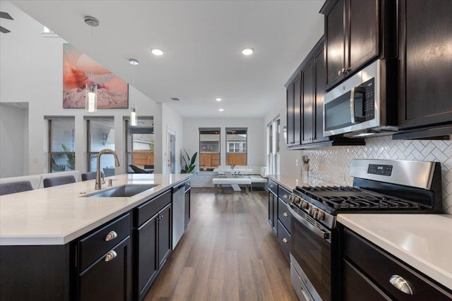 kitchen with dark wood-style flooring, a sink, light countertops, open floor plan, and stainless steel appliances