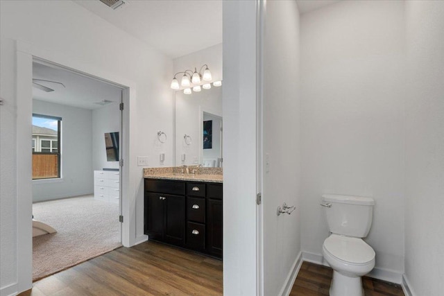bathroom with toilet, baseboards, wood finished floors, and vanity