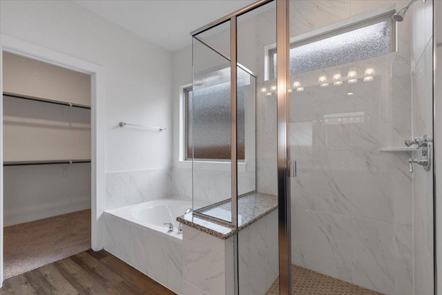bathroom featuring a wealth of natural light, a marble finish shower, and wood finished floors