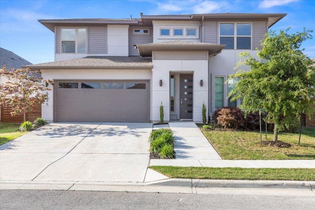 prairie-style house featuring concrete driveway, an attached garage, and stucco siding