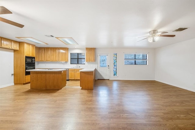 kitchen featuring light wood-style floors, a center island, visible vents, and black appliances
