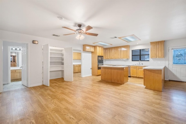 kitchen featuring a sink, visible vents, light countertops, a center island, and light wood finished floors