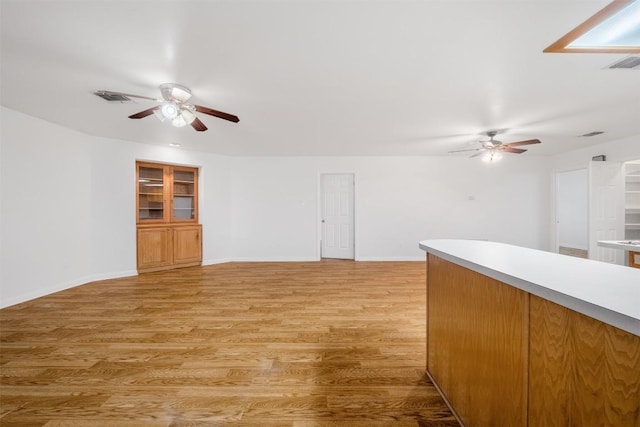 spare room featuring light wood finished floors, a ceiling fan, visible vents, and baseboards