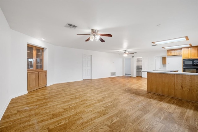 kitchen featuring light countertops, visible vents, light wood-style flooring, and black appliances