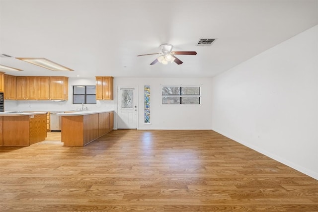 kitchen featuring visible vents, open floor plan, a peninsula, light countertops, and stainless steel dishwasher