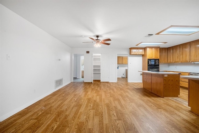 kitchen with visible vents, light wood-style floors, a center island, light countertops, and black appliances