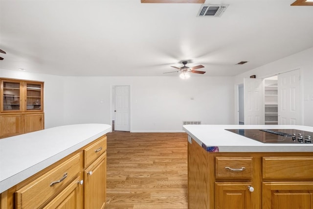 kitchen featuring ceiling fan, black electric cooktop, visible vents, light countertops, and light wood finished floors