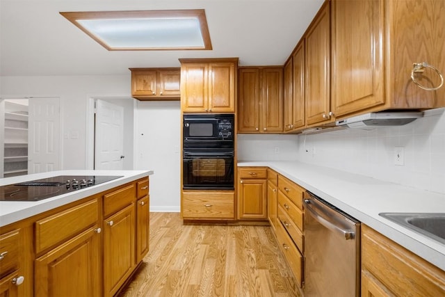 kitchen featuring light wood-type flooring, black appliances, brown cabinets, and light countertops
