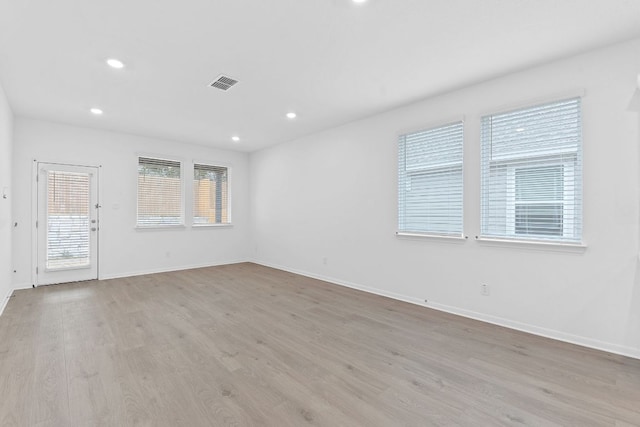 unfurnished room with baseboards, light wood-style flooring, visible vents, and recessed lighting