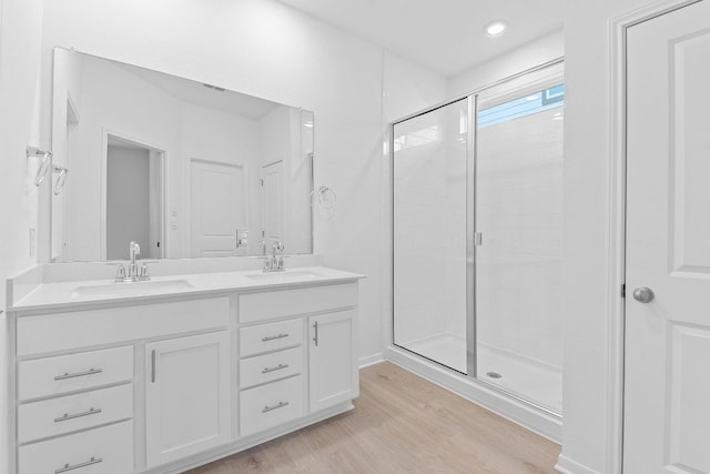 full bath featuring a sink, a shower stall, and wood finished floors