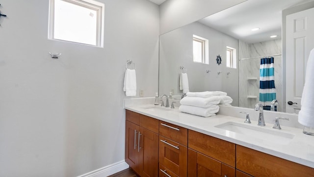 full bathroom with curtained shower, a sink, baseboards, and double vanity