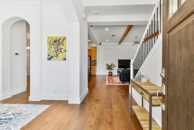 entrance foyer with arched walkways, hardwood / wood-style flooring, baseboards, stairway, and beam ceiling