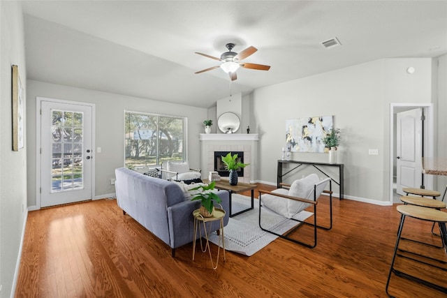 living room featuring baseboards, visible vents, ceiling fan, wood finished floors, and a fireplace