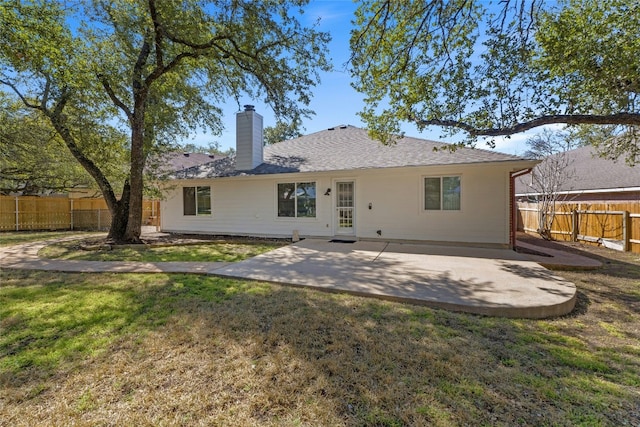 rear view of house with a patio, a yard, a chimney, and fence