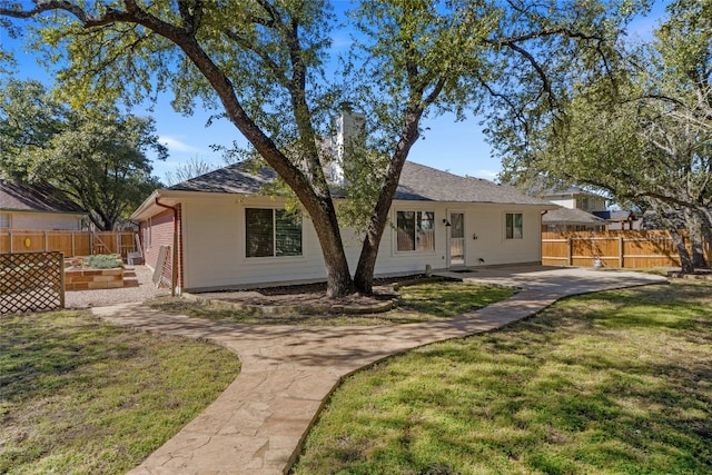 back of house featuring a yard, a patio area, fence, and a vegetable garden