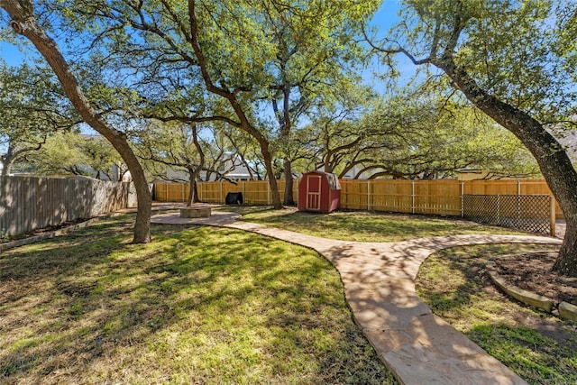 view of yard with a fenced backyard, an outdoor structure, and a storage unit