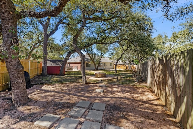 view of yard featuring an outbuilding, an outdoor fire pit, and a fenced backyard