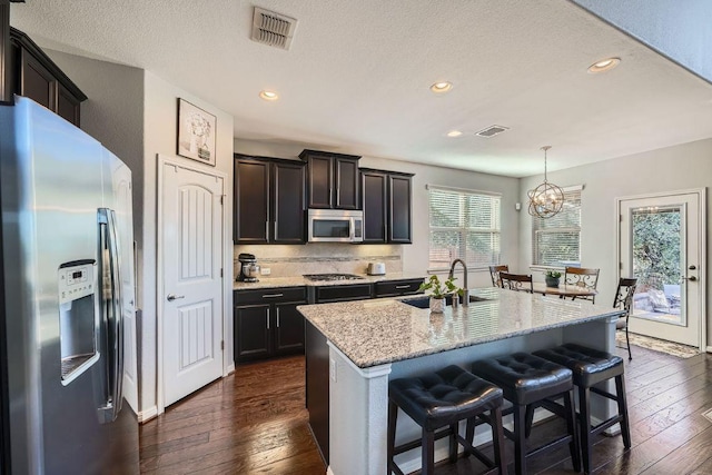 kitchen with appliances with stainless steel finishes, dark wood-type flooring, a sink, and visible vents