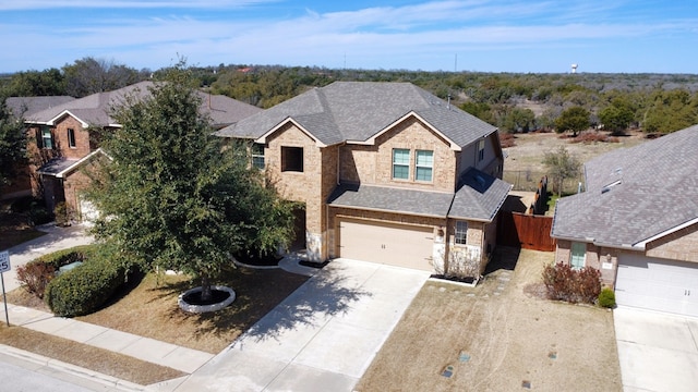 view of front of house with roof with shingles, an attached garage, fence, stone siding, and driveway