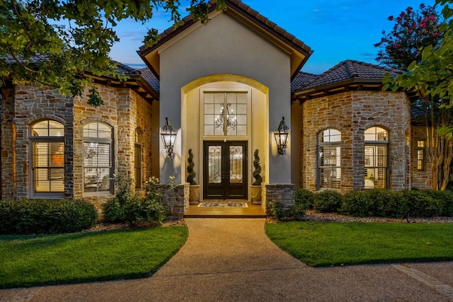 doorway to property with stone siding, french doors, a tiled roof, and stucco siding