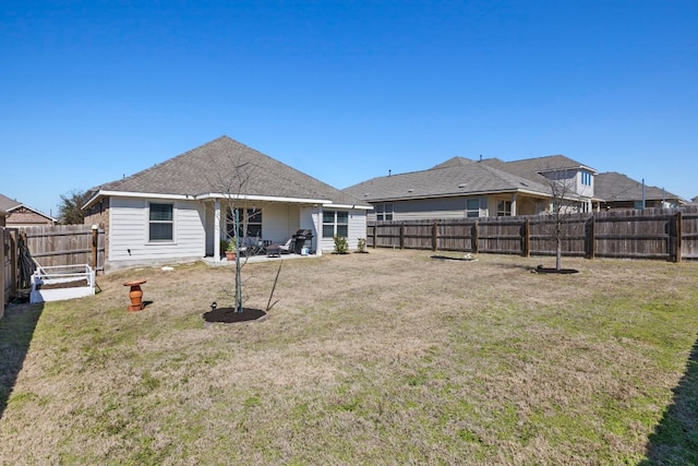 rear view of property with a fenced backyard and a lawn