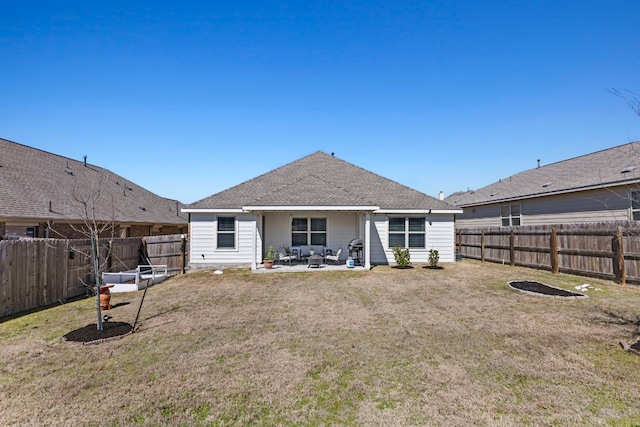 rear view of property with a shingled roof, a patio area, a fenced backyard, and a lawn