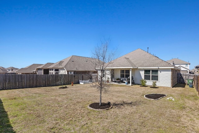 back of property with a shingled roof, a fenced backyard, a yard, and a patio