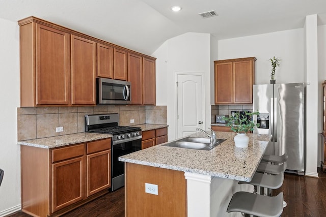 kitchen featuring a center island with sink, visible vents, vaulted ceiling, stainless steel appliances, and a sink