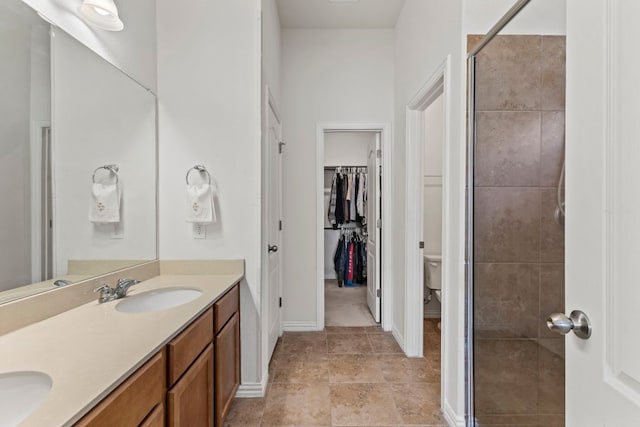 bathroom featuring toilet, a sink, a spacious closet, double vanity, and a stall shower