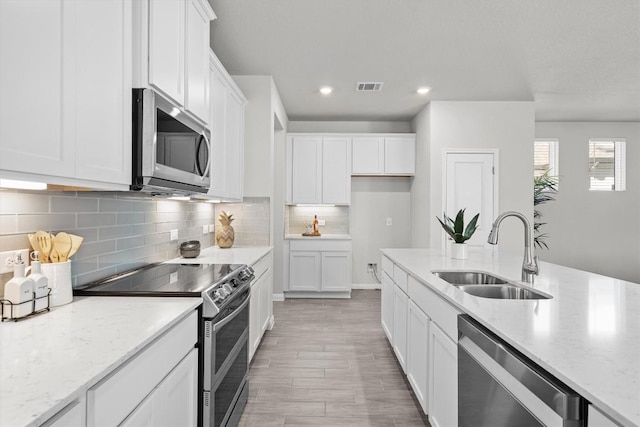 kitchen with white cabinets, visible vents, stainless steel appliances, and a sink