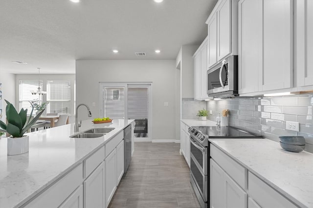 kitchen featuring tasteful backsplash, recessed lighting, appliances with stainless steel finishes, white cabinetry, and a sink