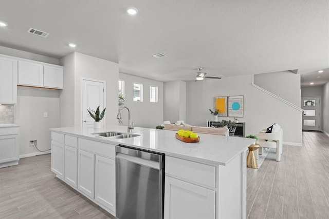 kitchen featuring stainless steel dishwasher, a sink, visible vents, and light wood-style floors