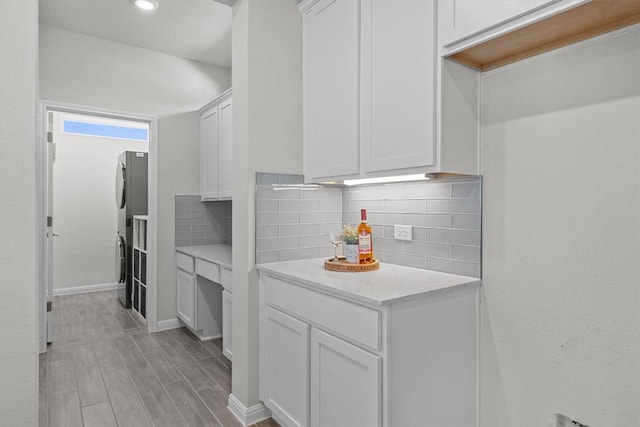 kitchen with tasteful backsplash, white cabinets, light wood-style flooring, freestanding refrigerator, and light countertops