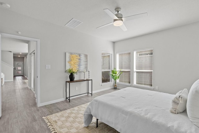 bedroom with baseboards, visible vents, ceiling fan, and wood finished floors