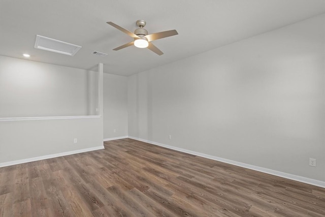 empty room with visible vents, attic access, ceiling fan, wood finished floors, and baseboards